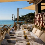 Set terrace tables under sail shades overlooking the coast at Loulou Restaurant Saint-Tropez