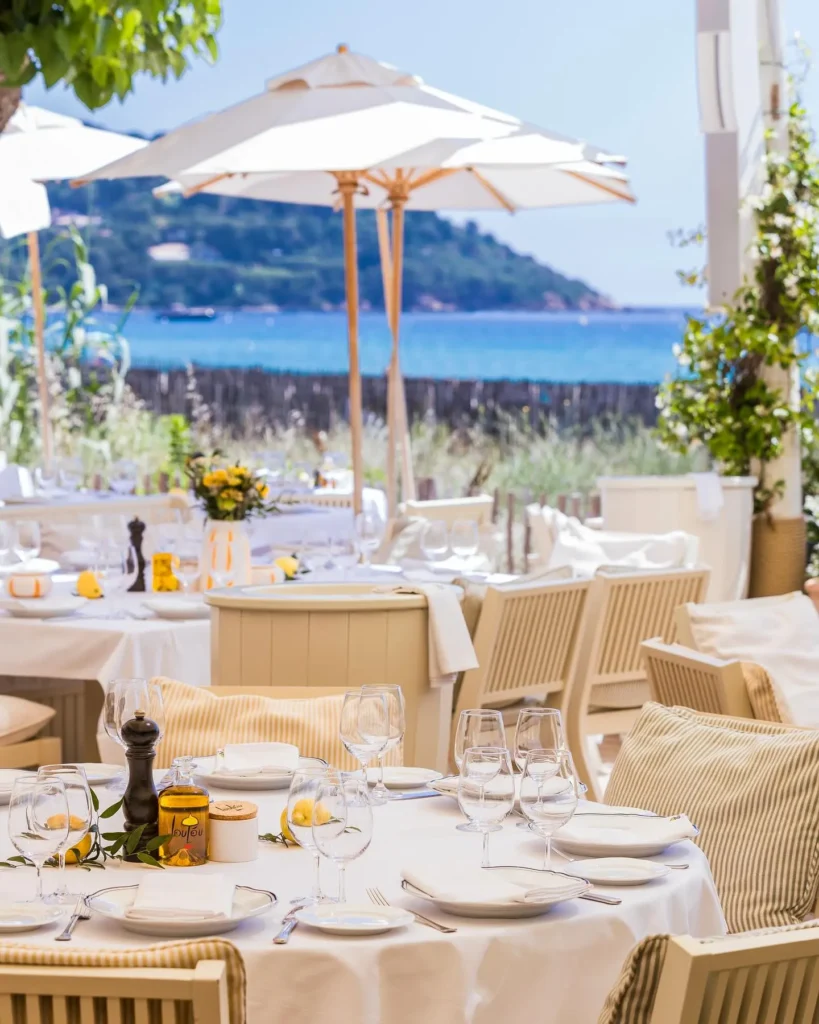 Set tables under white parasols facing the bay at Loulou Restaurant Saint-Tropez