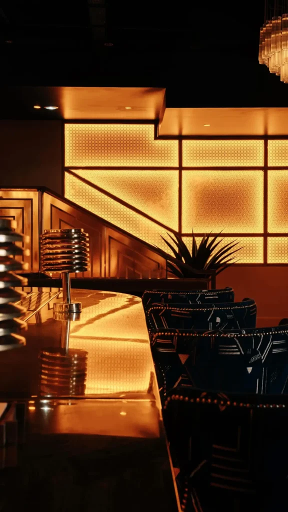 Brass bar counter with a backlit lattice screen and blue patterned armchairs at Manko Paris