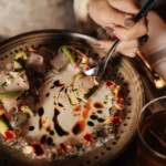 Fish ceviche in tiger's milk with avocado and marigold petals on a speckled bowl at Manko Paris