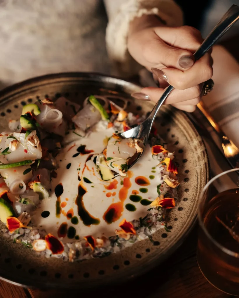 Fish ceviche in tiger's milk with avocado and marigold petals on a speckled bowl at Manko Paris