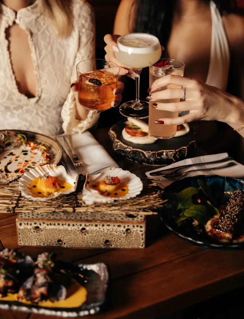 Guests toasting cocktails over scallops, ceviche and small plates at Manko Paris