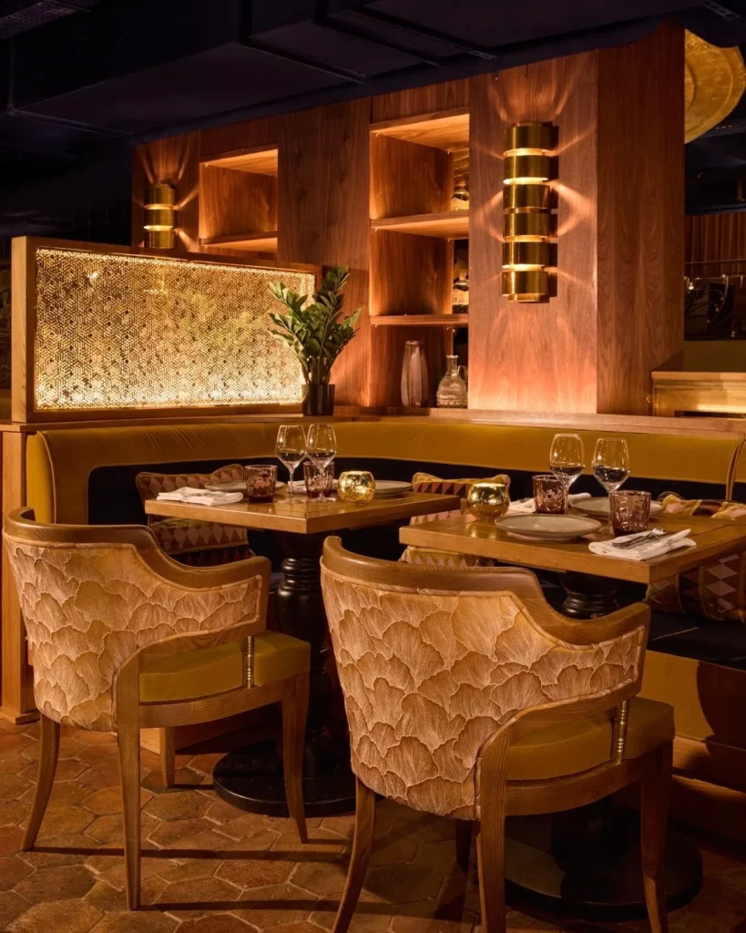 Ochre banquette and carved-back chairs by a gilded lattice screen at Manko Paris
