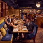 Banquette dining beside a blue-and-gold sea mosaic on a brick floor at Manko Paris