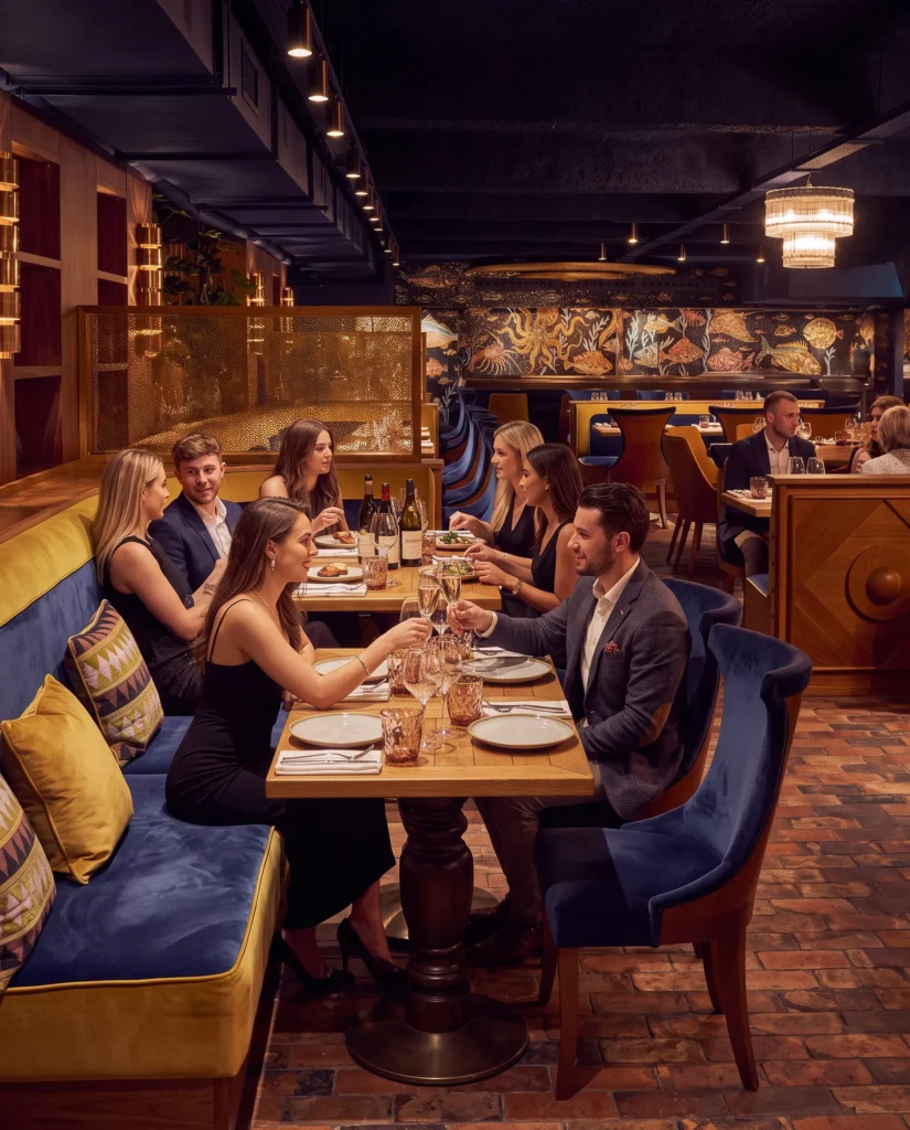 Banquette dining beside a blue-and-gold sea mosaic on a brick floor at Manko Paris