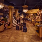 Grand Art Deco room with a sweeping gold staircase, tiered chandeliers and guests at Manko Paris