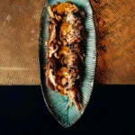Prawns with shiitake and salsa on an oval blue plate at Manko Paris