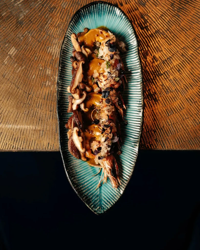 Prawns with shiitake and salsa on an oval blue plate at Manko Paris