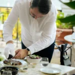 Gloved server carving a dish tableside on a marble table at Matsuhisa Saint-Tropez