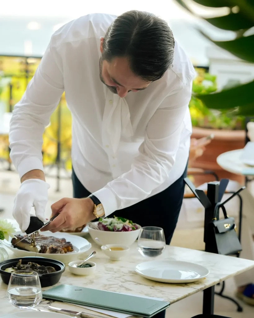 Gloved server carving a dish tableside on a marble table at Matsuhisa Saint-Tropez