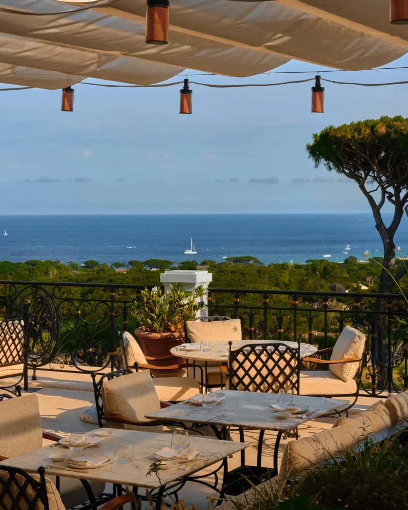 Terrace tables under a canopy with an umbrella pine and sea view at Matsuhisa Saint-Tropez