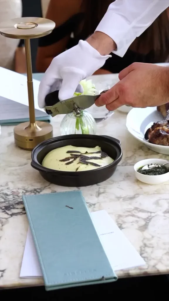 Gloved server shaving black truffle over mashed potato tableside at Matsuhisa Saint-Tropez