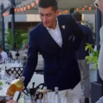 Sommelier in a navy blazer pouring wine at a terrace table at Matsuhisa Saint-Tropez