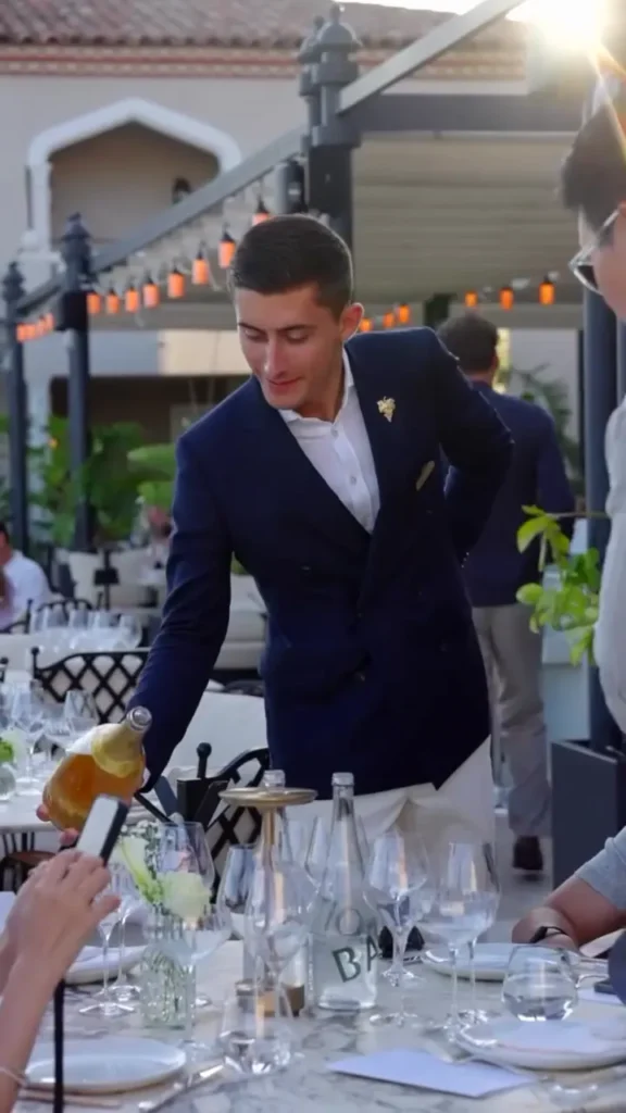 Sommelier in a navy blazer pouring wine at a terrace table at Matsuhisa Saint-Tropez