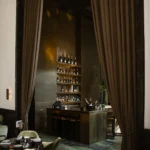 Tall curtained bar with backlit bottle shelves and green marble floor at Monsieur Bleu Paris
