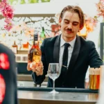Bartender presenting a bottle of rosé at a blossom-framed bar at Monsieur Bleu Paris