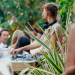 DJ performing among lush greenery to a crowd at Monsieur Bleu Paris