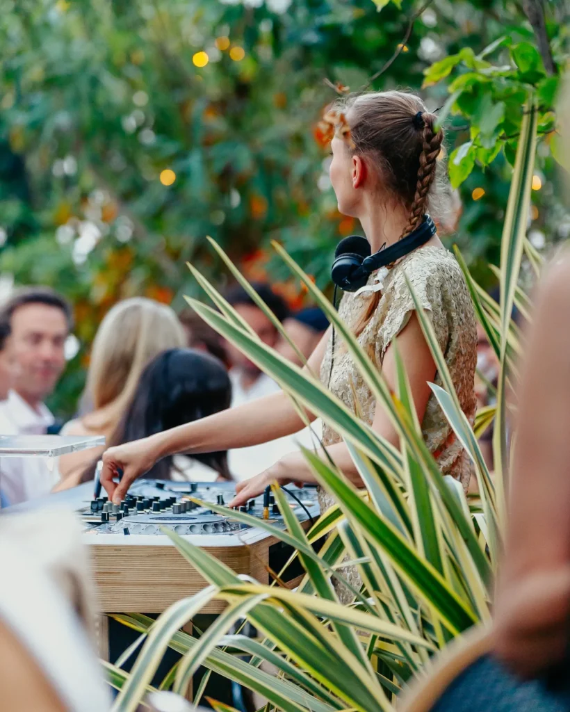 DJ performing among lush greenery to a crowd at Monsieur Bleu Paris