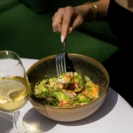 Prawn, quinoa and radish salad bowl beside a glass of white wine at Monsieur Bleu Paris