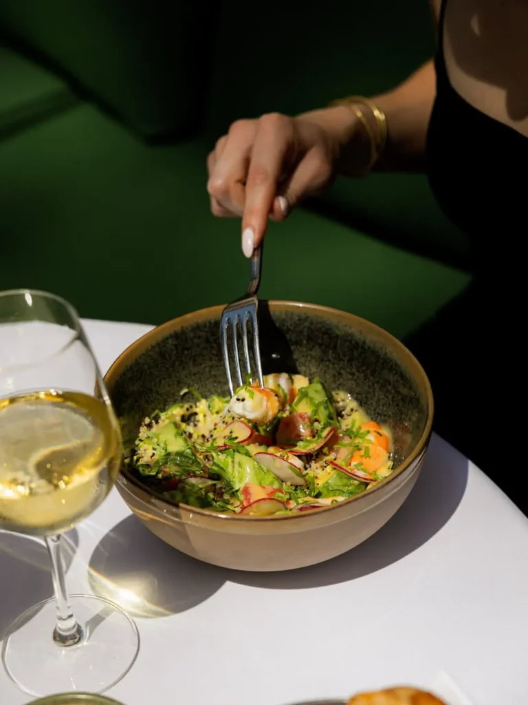 Prawn, quinoa and radish salad bowl beside a glass of white wine at Monsieur Bleu Paris