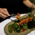Glazed sesame salmon over spinach on a green plate with white wine at Monsieur Bleu Paris