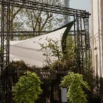 Monsieur Bleu sign above the planted entrance with the Eiffel Tower beyond the trees at Monsieur Bleu Paris