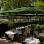 Terrace tables under a green parasol overlooking the Seine at Monsieur Bleu Paris