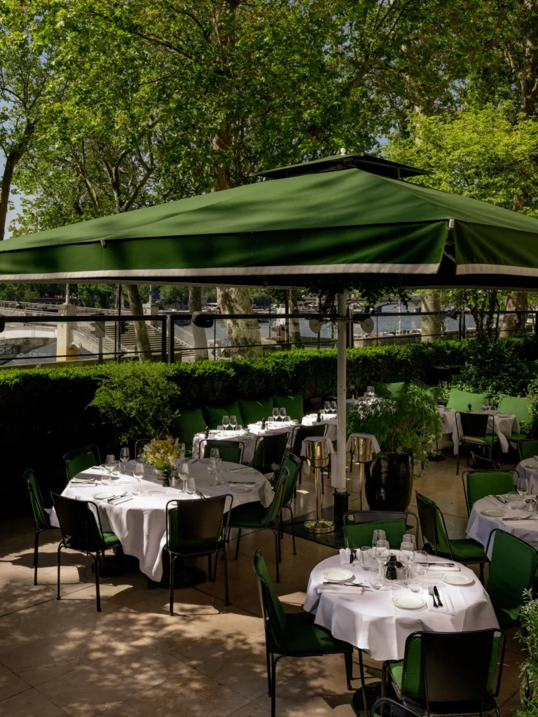 Terrace tables under a green parasol overlooking the Seine at Monsieur Bleu Paris