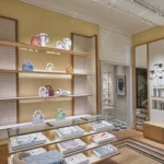 Boutique display of Lady Dior bags and scarves on wooden shelves at Monsieur Dior des Lices Saint-Tropez by Mauro Colagreco