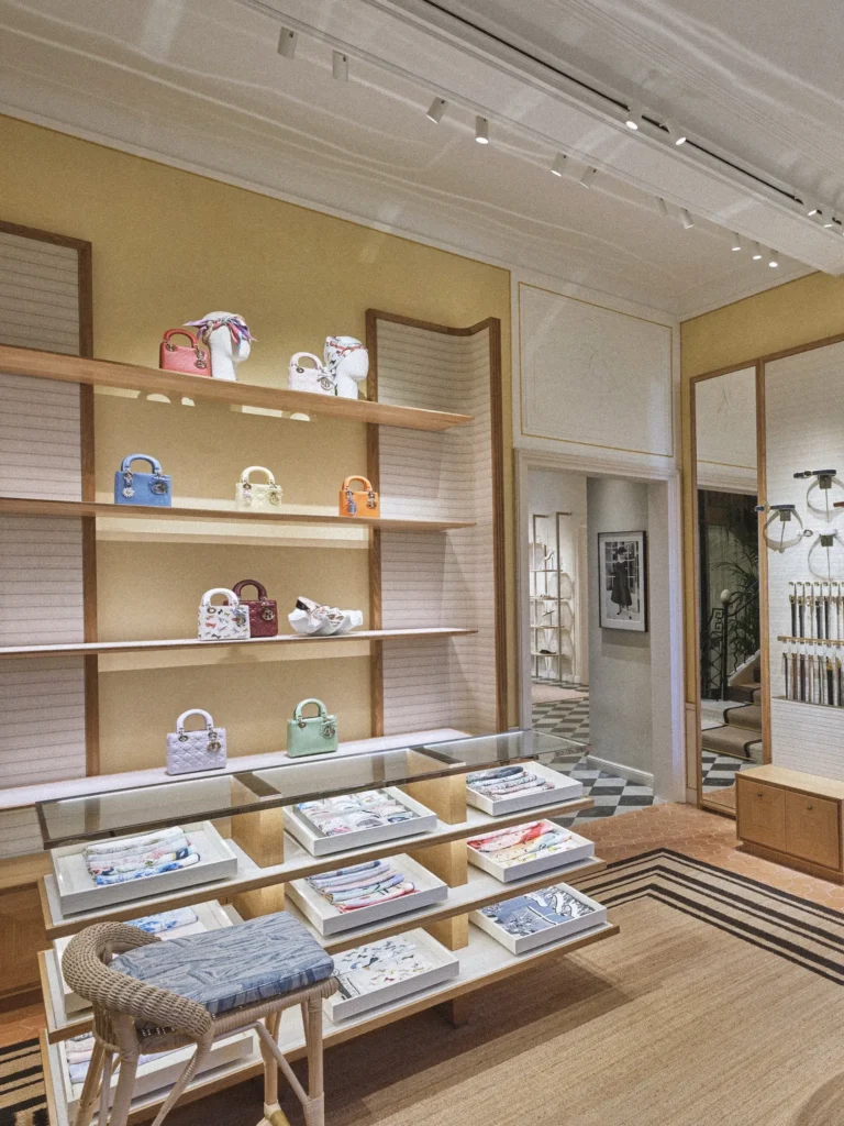Boutique display of Lady Dior bags and scarves on wooden shelves at Monsieur Dior des Lices Saint-Tropez by Mauro Colagreco