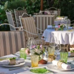 Outdoor tables set with green glassware and floral posies at Monsieur Dior des Lices Saint-Tropez by Mauro Colagreco