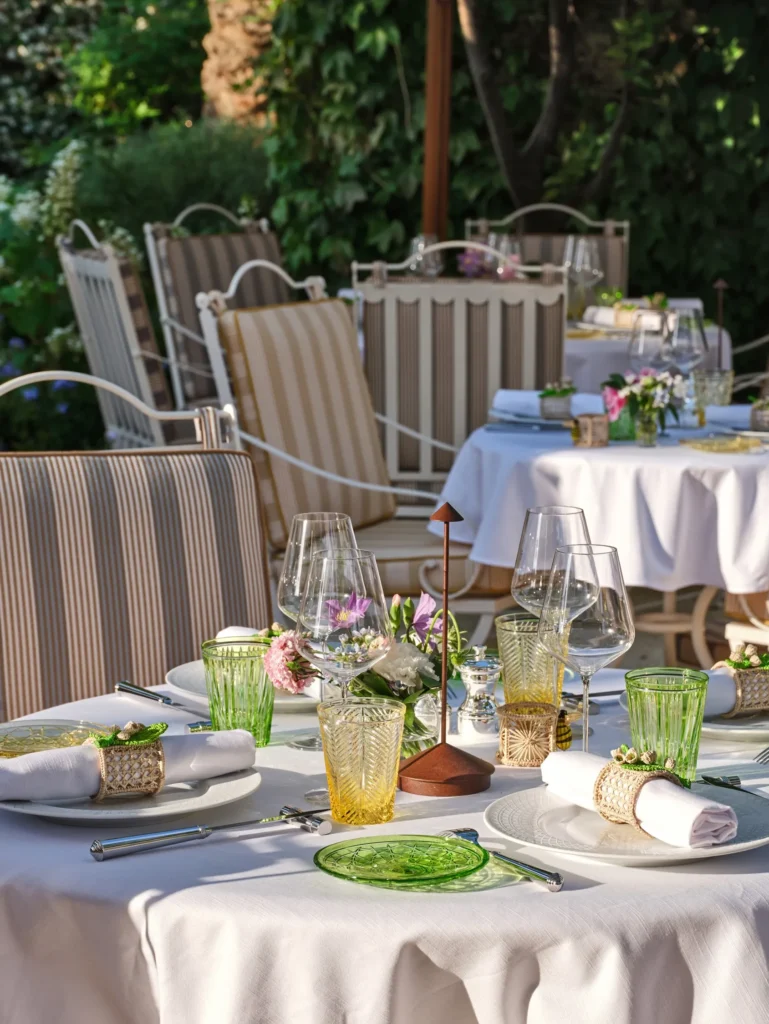 Outdoor tables set with green glassware and floral posies at Monsieur Dior des Lices Saint-Tropez by Mauro Colagreco