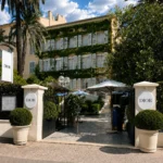 Open entrance flanked by two DIOR signs looking through to the garden courtyard at Monsieur Dior des Lices Saint-Tropez by Mauro Colagreco