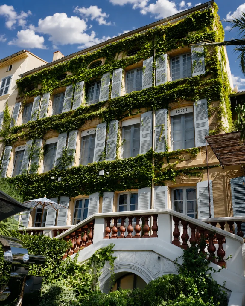 Ivy-clad facade with blue shutters and a balustraded staircase at Monsieur Dior des Lices Saint-Tropez by Mauro Colagreco