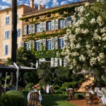 Rattan chairs and white-clothed tables on the lawn before the facade at Monsieur Dior des Lices Saint-Tropez by Mauro Colagreco