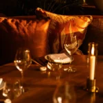 Candlelit table setting at NAŌ Saint-Tropez with wine glasses and silk cushions