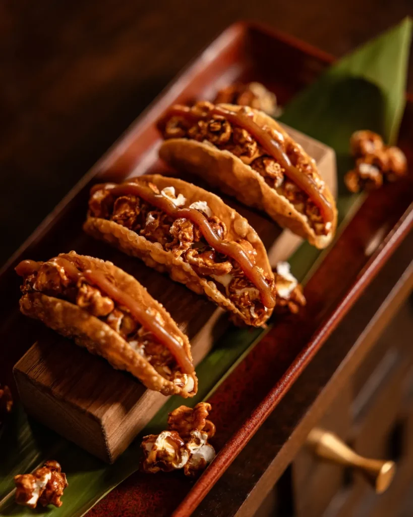 Caramel popcorn taco dessert plated on a wooden board at NAŌ Saint-Tropez