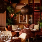 Intimate dining area at NAŌ Saint-Tropez with velvet chairs and woven pendant lamp