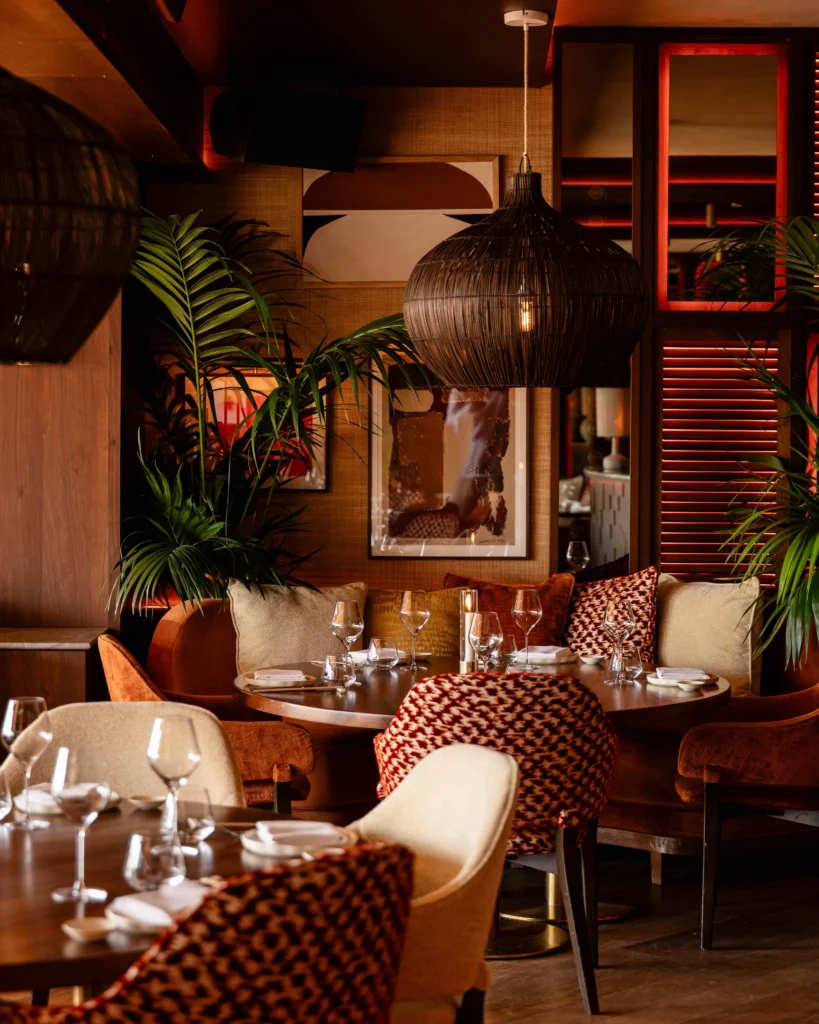 Intimate dining area at NAŌ Saint-Tropez with velvet chairs and woven pendant lamp
