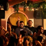 DJ performing to a lively crowd under an arched neon light at NAŌ Saint-Tropez