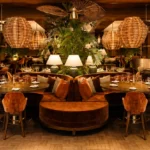 Main dining room at NAŌ Saint-Tropez with rattan pendant lights and central round booth