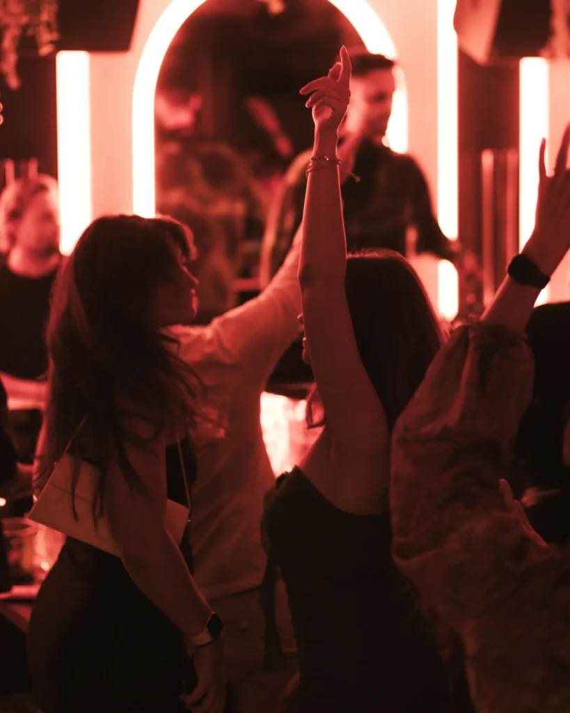 Guests dancing under red neon lighting during nightlife at NAŌ Saint-Tropez