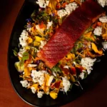 Glazed salmon dish garnished with edible flowers and puffed rice at NAŌ Saint-Tropez