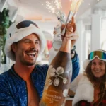 Guests in sequins celebrating with a sparkler-topped champagne bottle at Nikki Beach Saint Barth