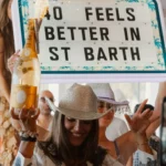 Guest holding a sparkler-topped champagne bottle beneath a Nikki Beach letter-board sign at Nikki Beach Saint Barth