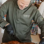 Chef carving a tomahawk steak tableside at Nikki Beach Saint Barth