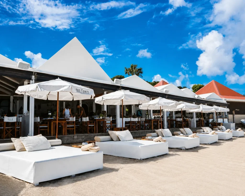 White daybeds and branded parasols in front of the beachfront restaurant at Nikki Beach Saint Barth