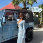 Guest posing beside a pale blue open-top jeep at the Nikki Beach arch at Nikki Beach Saint Barth