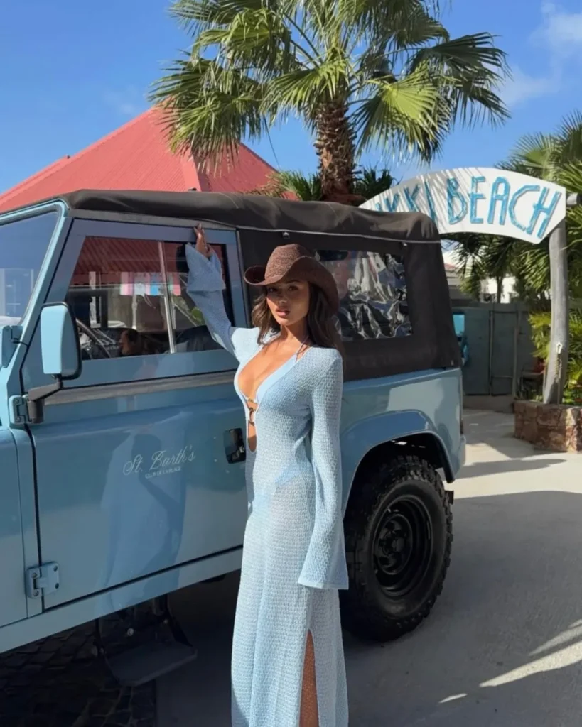Guest posing beside a pale blue open-top jeep at the Nikki Beach arch at Nikki Beach Saint Barth