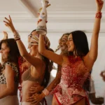 Guests dancing with hands raised and a bottle held aloft at Nikki Beach Saint Barth